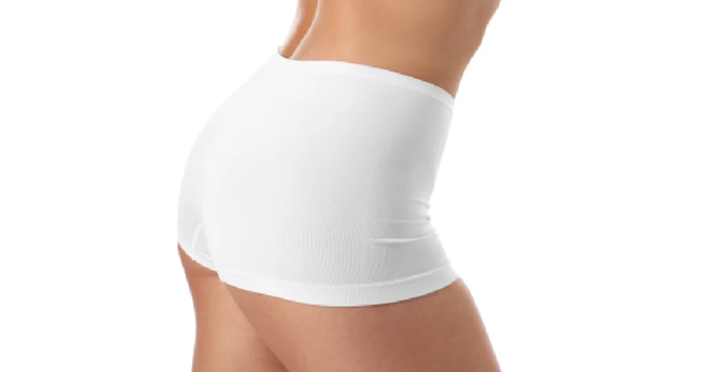 Woman showing toned curves after Booty Enhancement in Oklahoma City, wearing white fitted shorts.